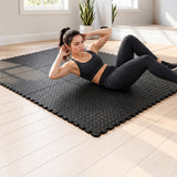 Woman exercising on connected plain black EVA foam floor tiles with interlocking puzzle edges.