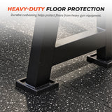 Rubber gym flooring tiles under a weight rack, showing the cushioned surface beneath gym equipment.