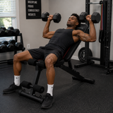 Man performing an incline dumbbell press on the adjustable workout bench in a home gym