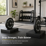 Loaded barbell resting on two MotionGrey drop pads in a home gym