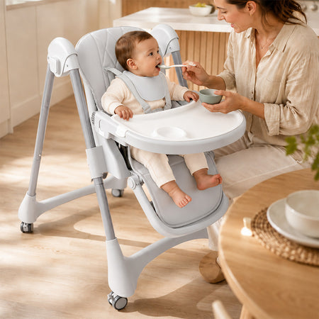 Caregiver feeding a baby seated securely in the gray adjustable high chair