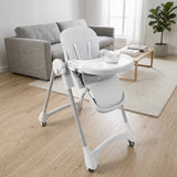 Gray adjustable baby high chair with a bowl and spoon in a bright living room