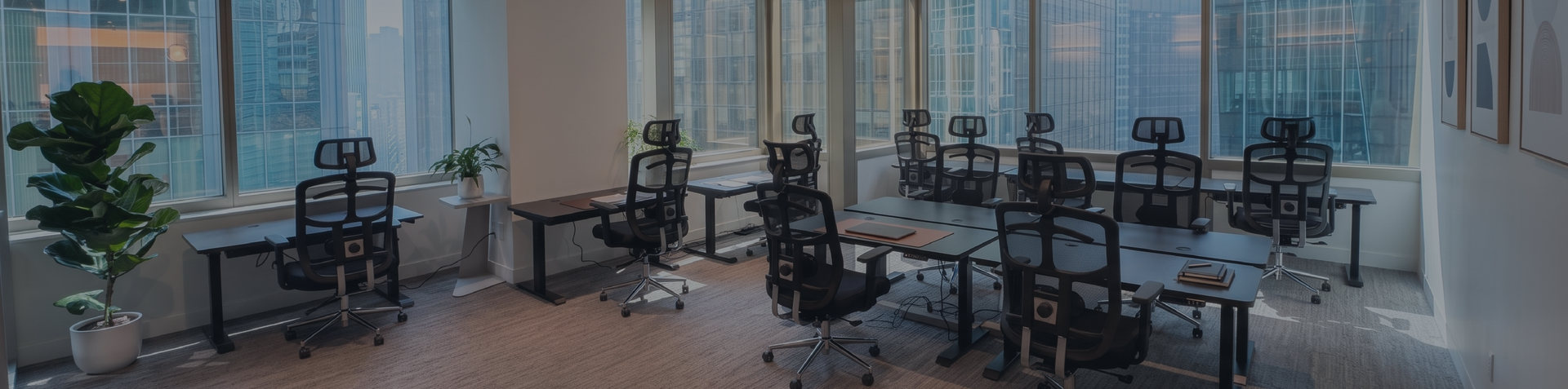 Modern open-plan office with MotionGrey ergonomic standing desks and mesh chairs overlooking city skyline
