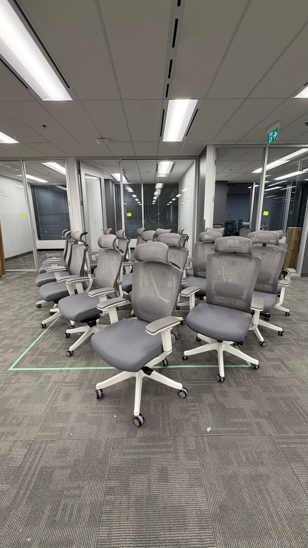 Rows of assembled grey CloudMesh office chairs with white bases at MapsPeople’s Richmond Hill office.