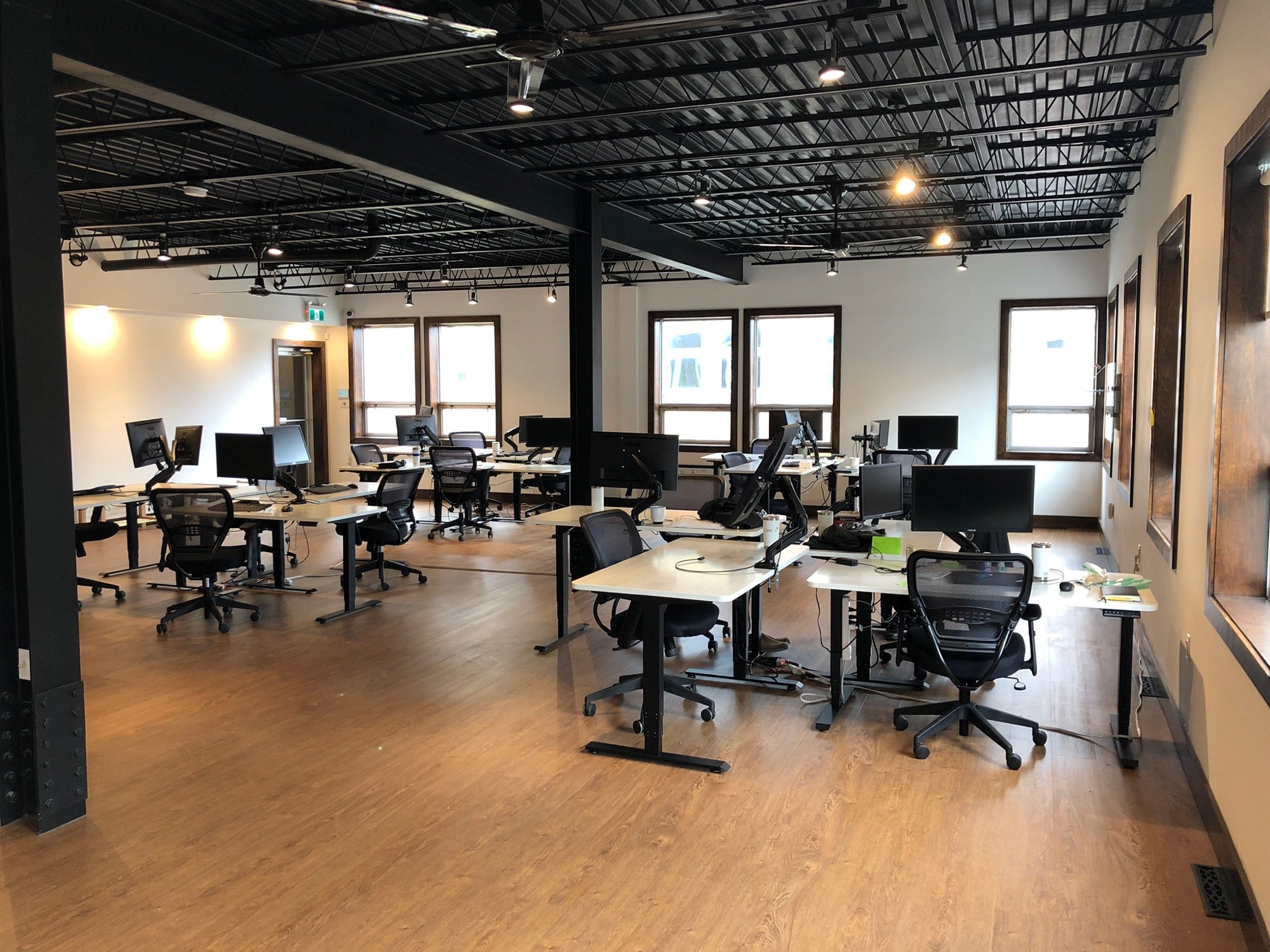 Motion Series standing desks with light desktops and dark frames alongside black SkyMesh office chairs in the Gatineau office.